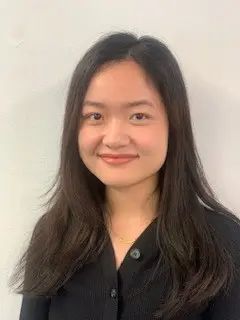 A woman with long dark hair and a black button-up shirt, smiling at the camera.