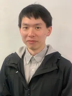 A man with dark hair, a light collared shirt and a dark jacket, facing the camera.